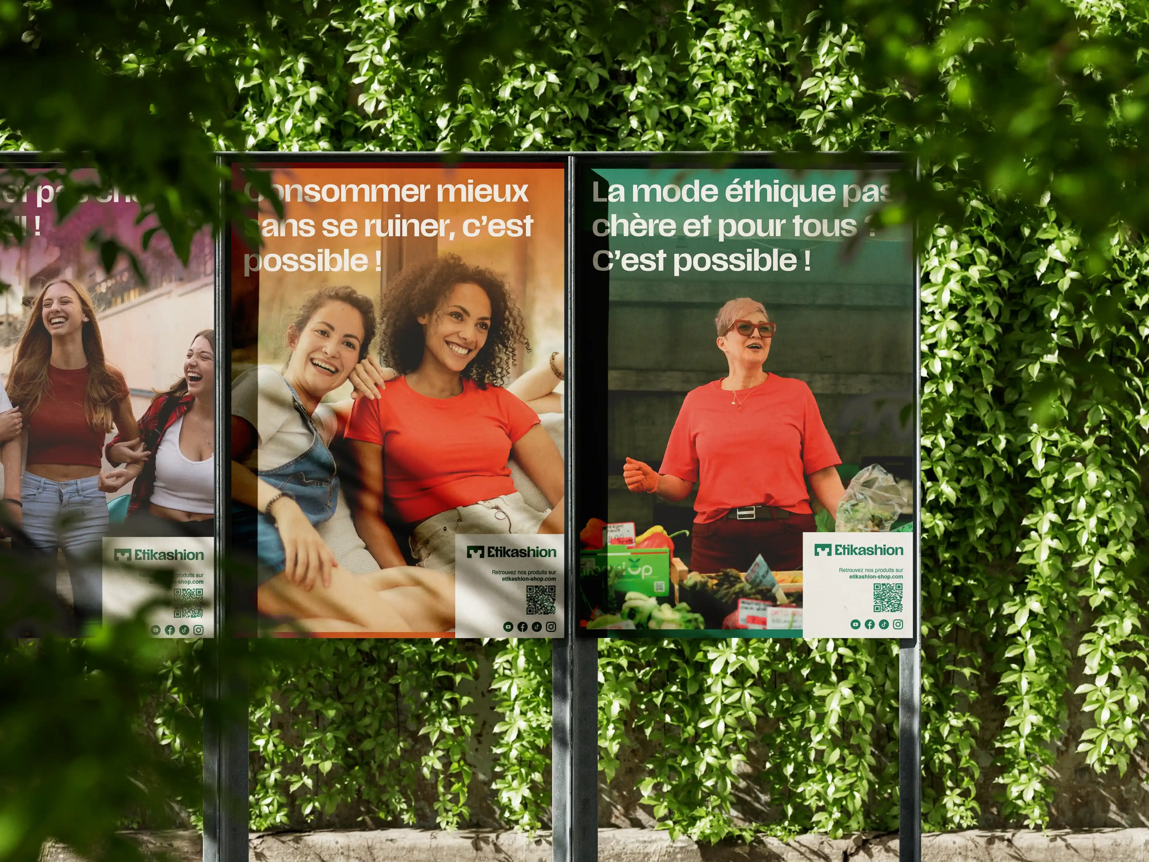 Photo de trois affiches promotionnelles pour Etikashion, placées dans un parc, devant un mur de lierre. La première affiche est rose mais n'est pas lisible. La deuxième est orange et indique : 'Consommer mieux sans se ruiner, c'est possible !' avec l'image de deux femmes souriantes. La troisième est verte et indique : 'La mode éthique pas chère et poiur tous ? C'est possible !' avec la photo d'une femme souriante.