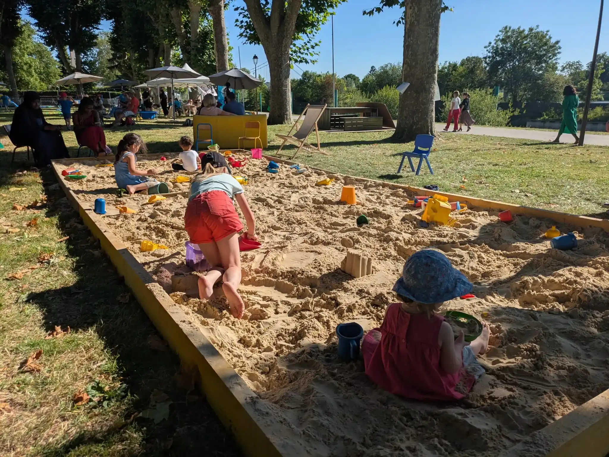 Photo d'enfants jouant dans un bac à sable sous un beau soleil.