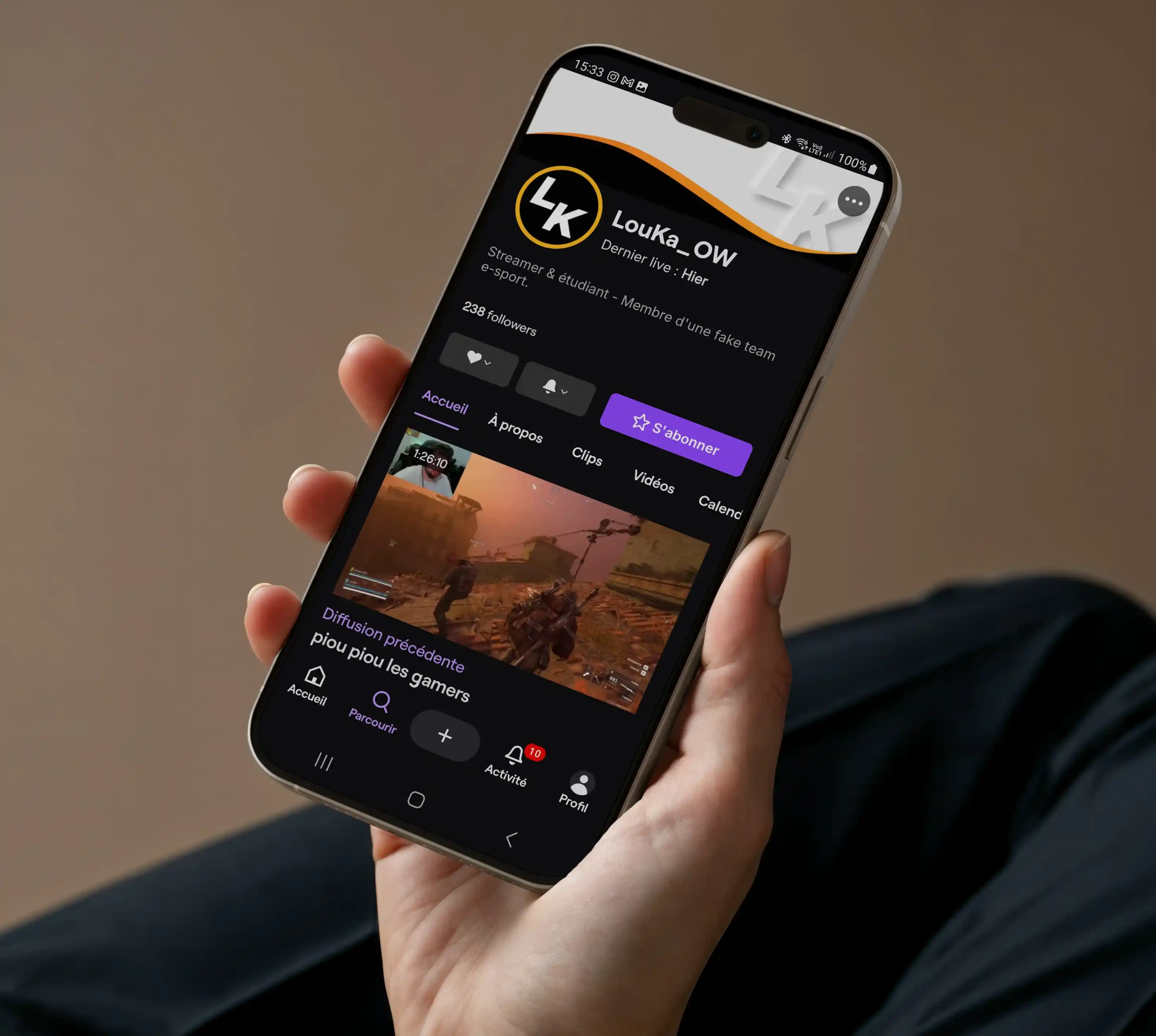 Photo d'une personne tenant un téléphone sur lequel se trouve la page d'accueil de la chaîne Twitch du streamer Louka_OW.